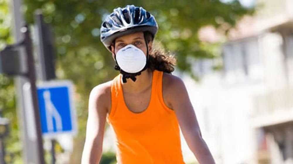 Kolesarska z obrazno masko opravlja kolesarski trening
